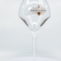 Verre à vin Domaine Pilènium transparent avec logo doré sur fond blanc minimaliste
