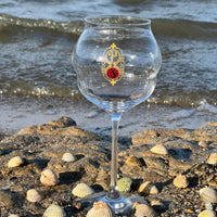 Verre à pied Pilenium Macaron en verre transparent sur rocher avec coquillages, plage et mer en arrière-plan