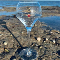 Verre à vin Domaine de Pilenium posé sur un rocher près de la mer avec ciel bleu