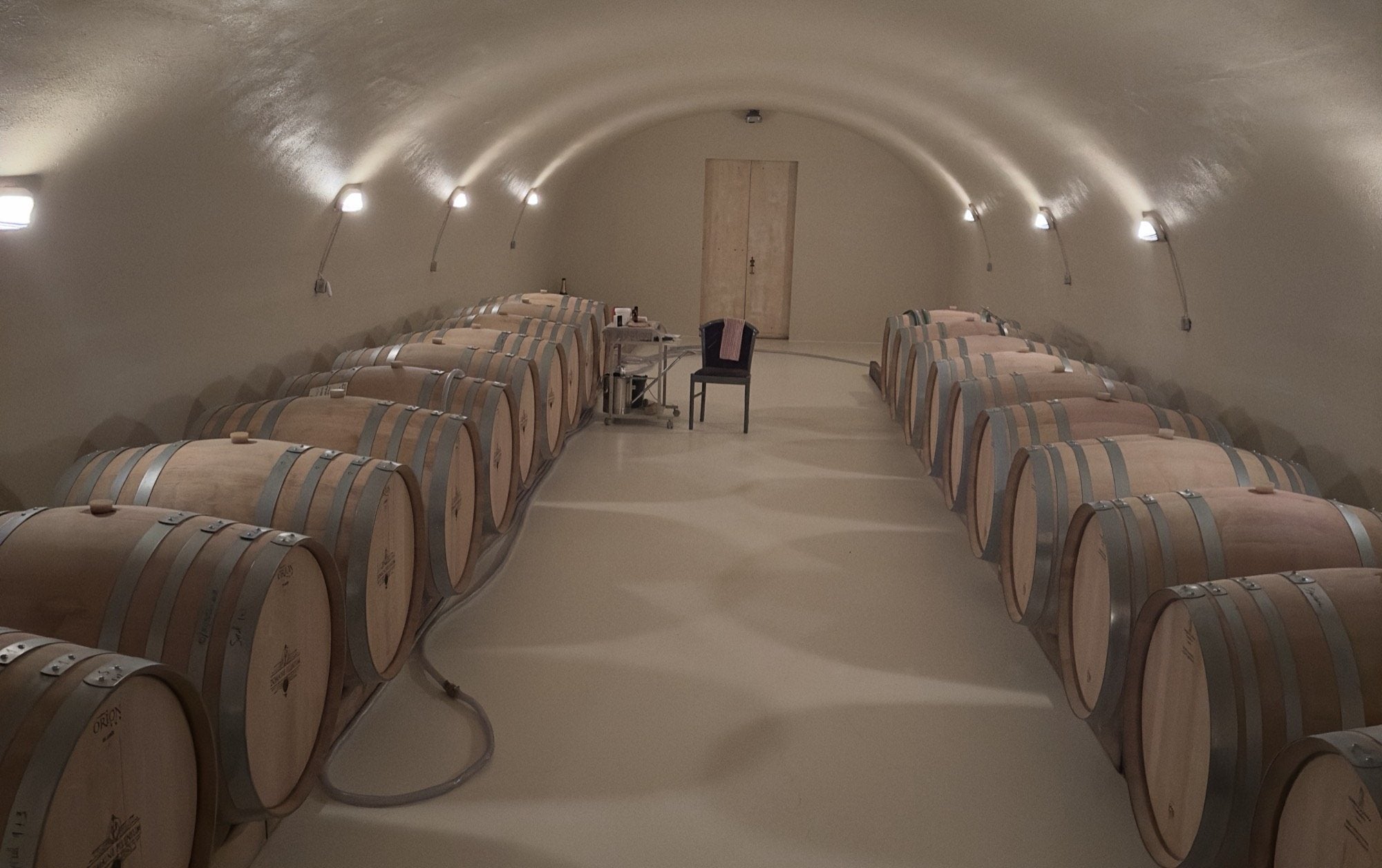 Le chai voûté d'élevage du Domaine Pilenium : deux rangées de barriques de chêne sous la voûte — élevage des cuvées en AOP Corbières biologique